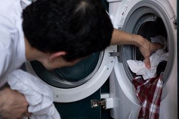 a man putting a shirt into a washing machine